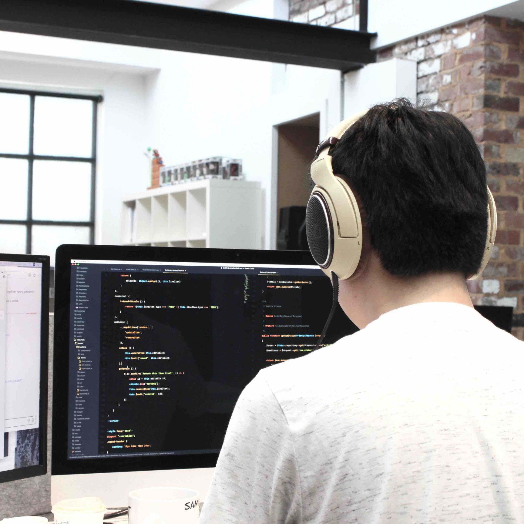 Man sitting at desk with large monitor writing computer code